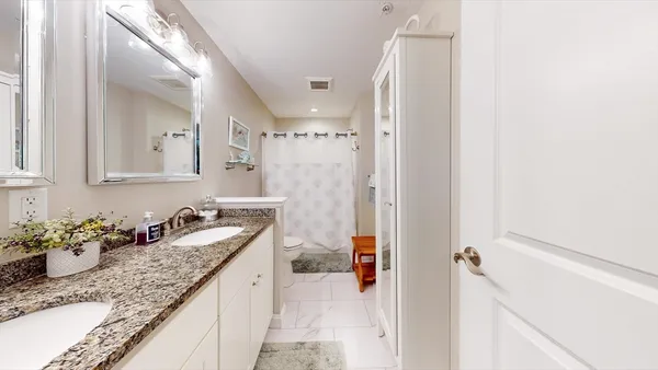 a bathroom with a granite countertop sink mirror and a shower