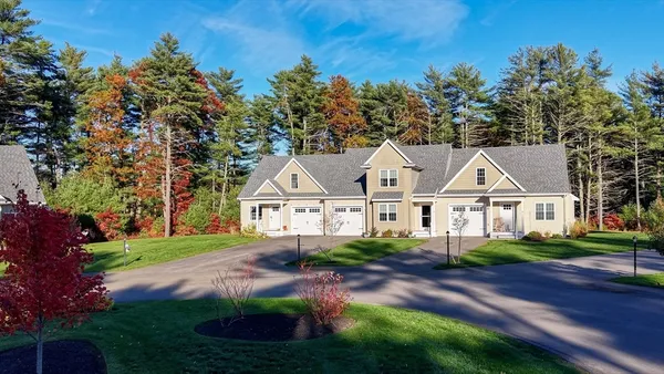 a front view of a house with a garden and trees
