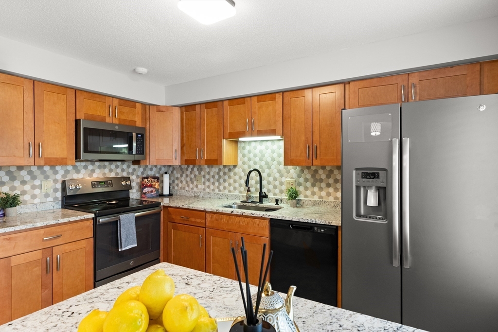4203 Woodbridge Road, Unit 4203 Peabody, MA 01960 - Photo 8 of 31 a kitchen with stainless steel appliances granite countertop a refrigerator and a stove top oven