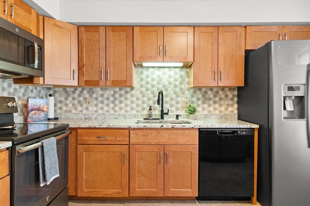 4203 Woodbridge Road, Unit 4203 Peabody, MA 01960 - Photo 9 of 31 a kitchen with stainless steel appliances granite countertop a sink stove and microwave