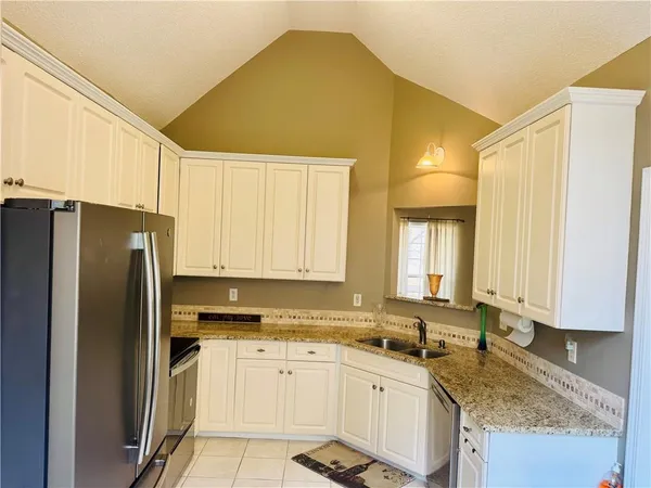 a kitchen with stainless steel appliances granite countertop a sink a refrigerator and a granite counter tops
