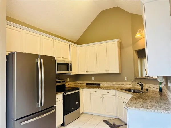 a kitchen with granite countertop a sink cabinets and stainless steel appliances