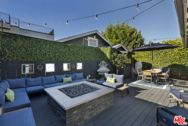 a view of a patio with couches table and chairs under an umbrella with wooden floor