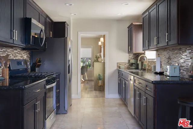 a kitchen with stainless steel appliances granite countertop a stove top oven a sink dishwasher a refrigerator and a cabinets