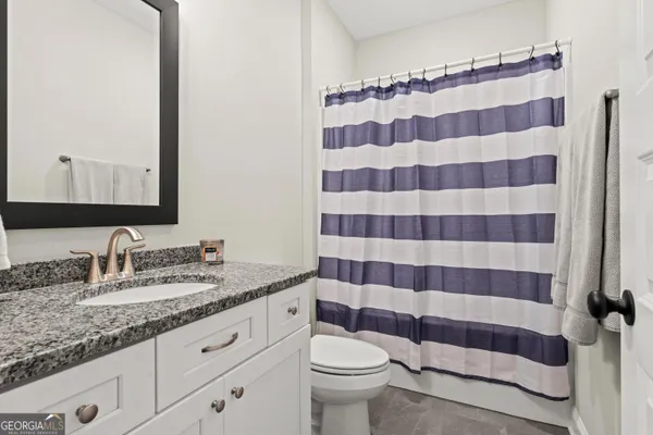 a bathroom with a sink a toilet a mirror and shower curtain