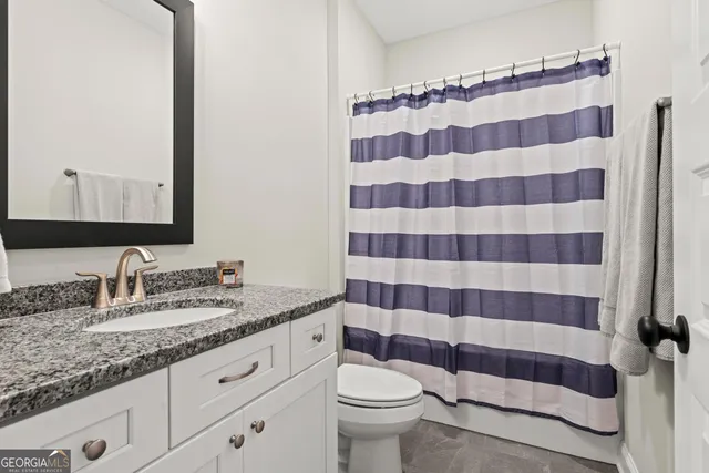a bathroom with a sink a toilet a mirror and shower curtain