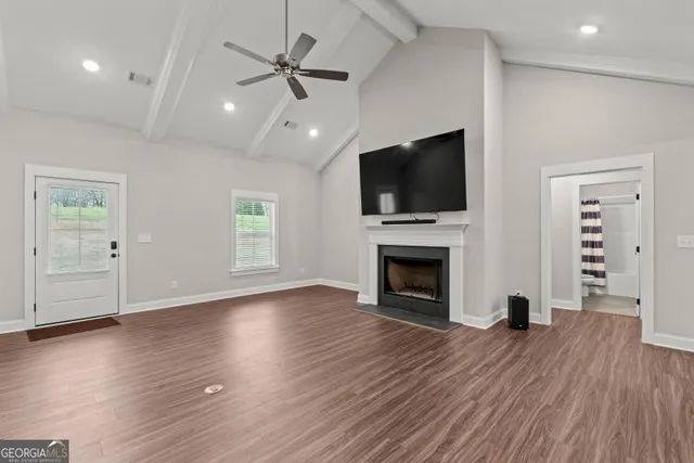 an empty room with fireplace wooden floor chandelier fan and windows