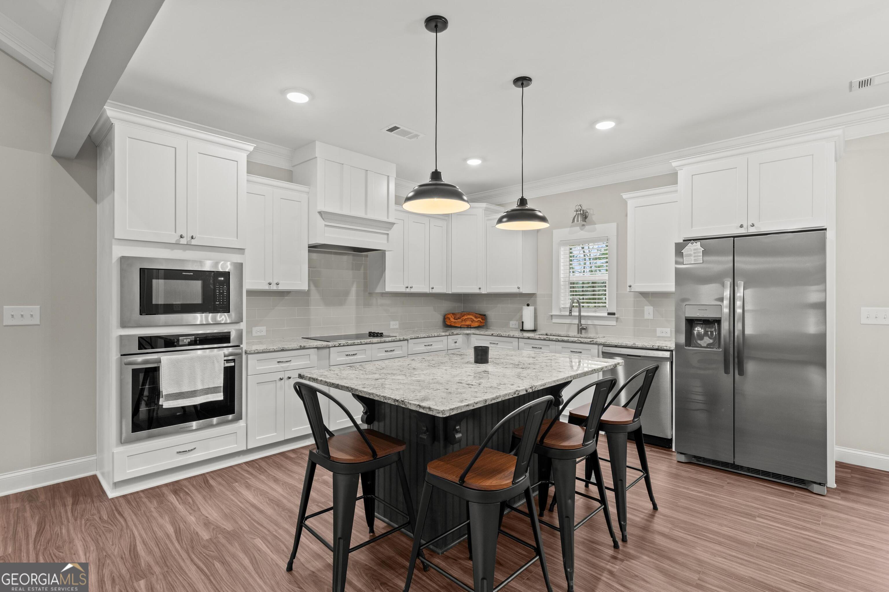 340 Happy Hollow Road Roopville, GA 30170 - Photo 7 of 22 a kitchen with stainless steel appliances granite countertop a stove a kitchen island a refrigerator a stove a dining table and chairs with wooden floor