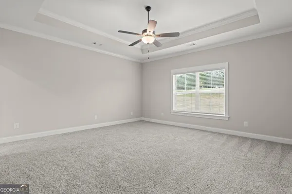 an empty room with a chandelier fan and windows