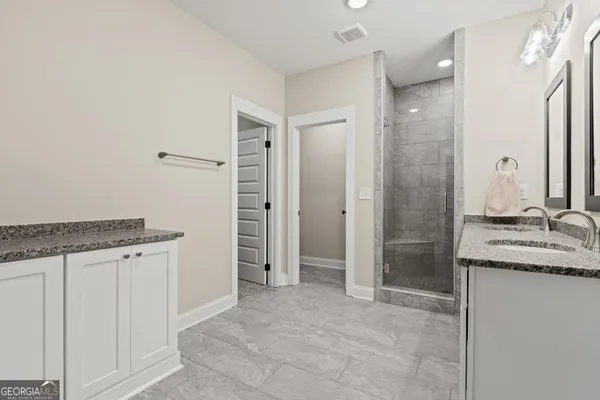 a bathroom with a granite countertop sink a mirror and a shower