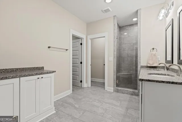 a bathroom with a granite countertop sink a mirror and a shower
