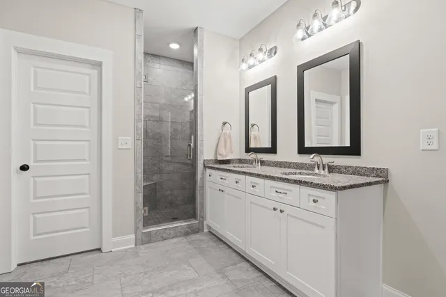 a bathroom with a granite countertop sink a mirror and a shower