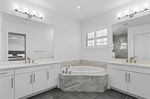 a bathroom with a granite countertop bathtub sink double and mirror