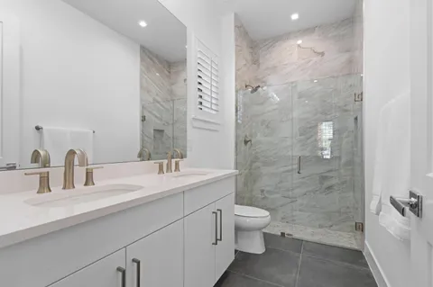 a bathroom with a double vanity sink toilet and shower