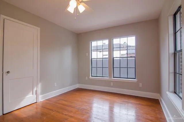 an empty room with wooden floor and windows