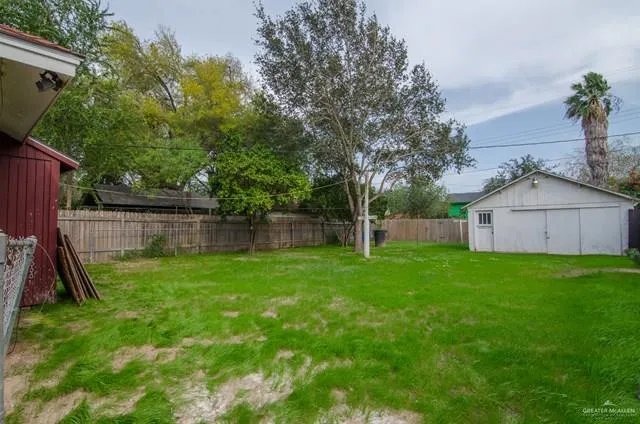 a view of a backyard with a tree and wooden fence