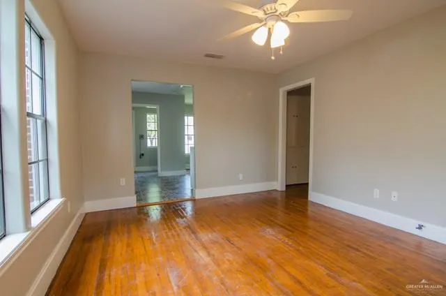 a view of an empty room with wooden floor and a window