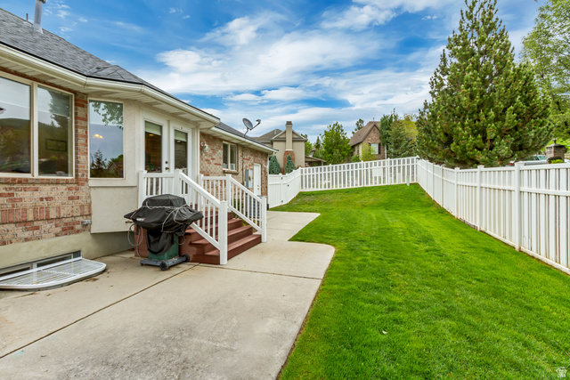 298 North Canyon Road Bountiful, UT 84010 - Photo 55 of 57 Expansive fenced backyard featuring a concrete patio, wood steps with white railings, and a wide grassy area