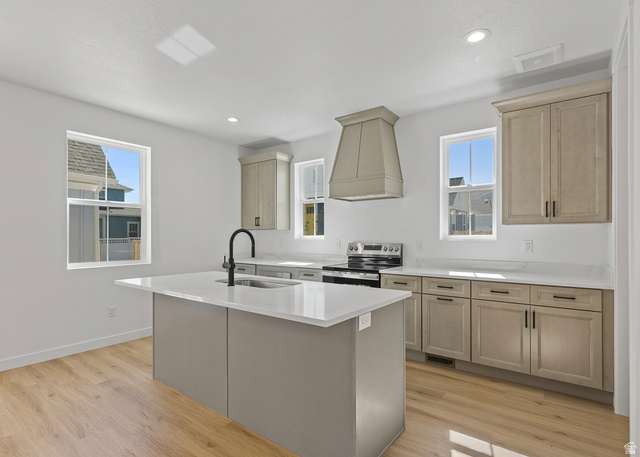 11214 South Easy Bee Road, Unit 270 South Jordan, UT 84009 - Photo 7 of 31 Contemporary kitchen featuring a center island with sink, white countertops, coordinating cabinetry, a range with hood, and wood-finish flooring
