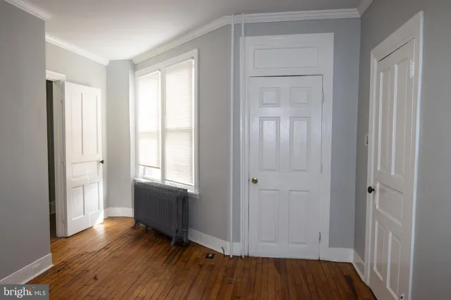 a view of an empty room with window and wooden floor