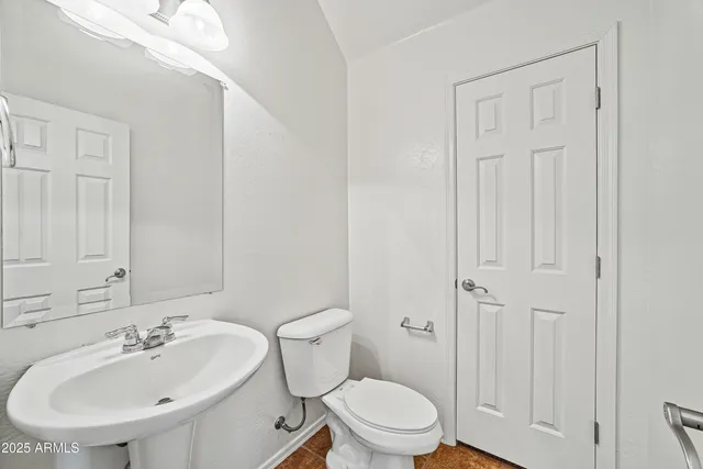 an empty room with kitchen view and a chandelier fan