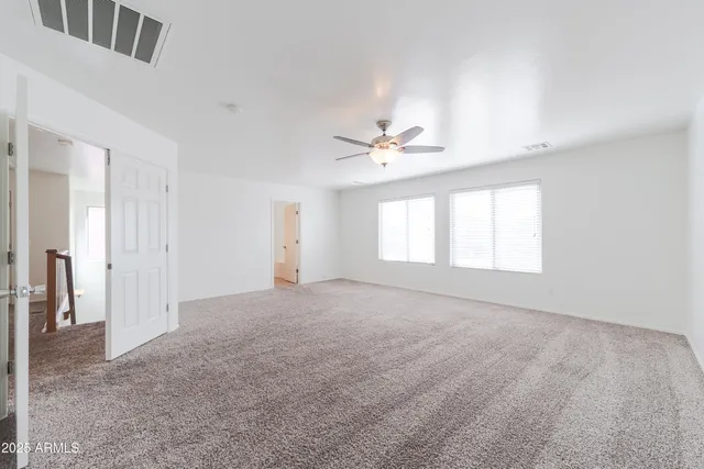 an empty room with windows and fan