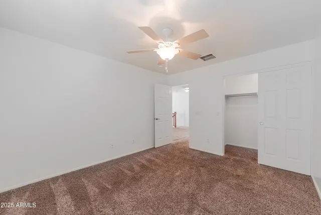 an empty room with a window and a ceiling fan