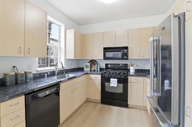 a kitchen with stainless steel appliances granite countertop a refrigerator a stove a sink and a microwave