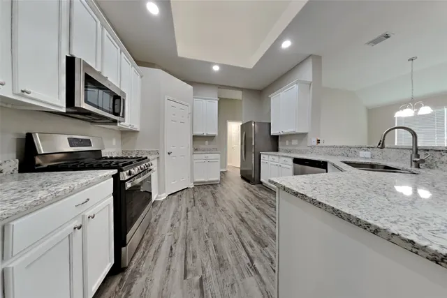 a kitchen with stainless steel appliances granite countertop a sink stove microwave and refrigerator