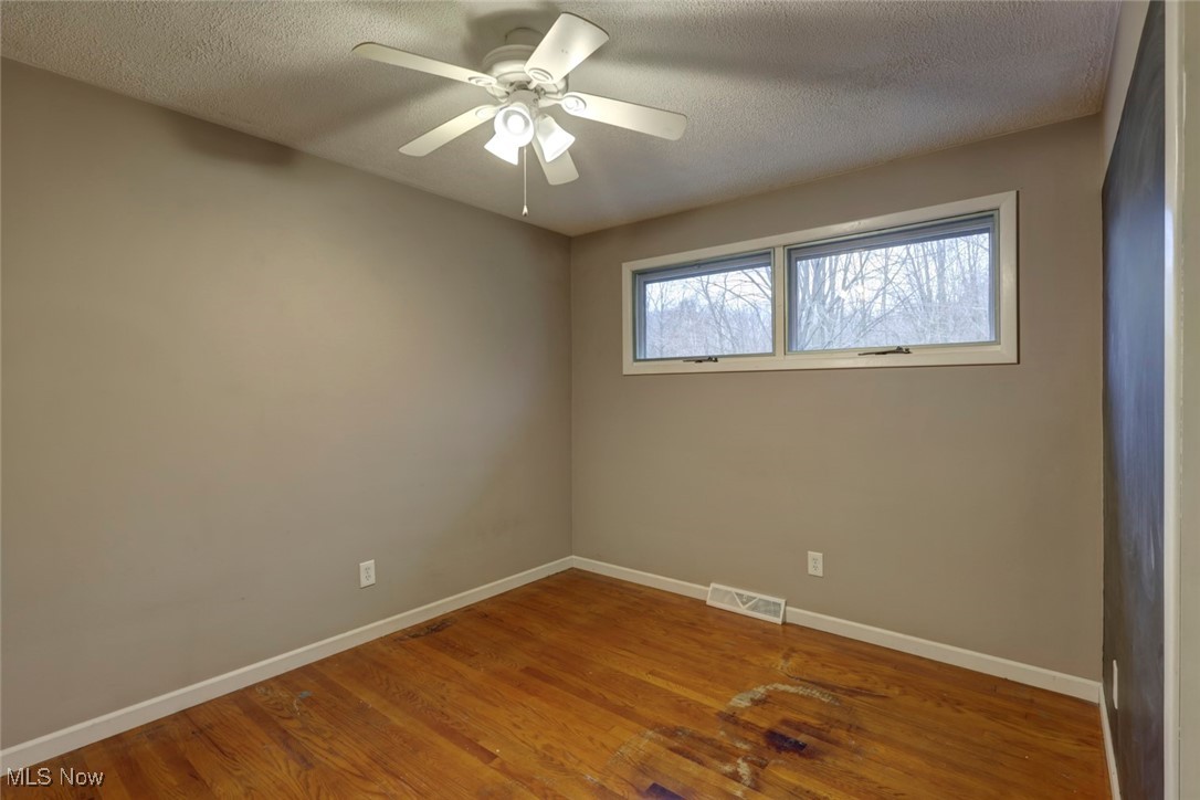 8104 Barnes Road Vermilion, OH 44089 - Photo 20 of 40 Unfurnished bedroom featuring ceiling fan, hardwood / wood-style floors, and a textured ceiling
