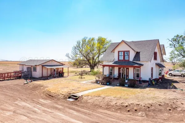 a view of a white house with a yard with snow and plants
