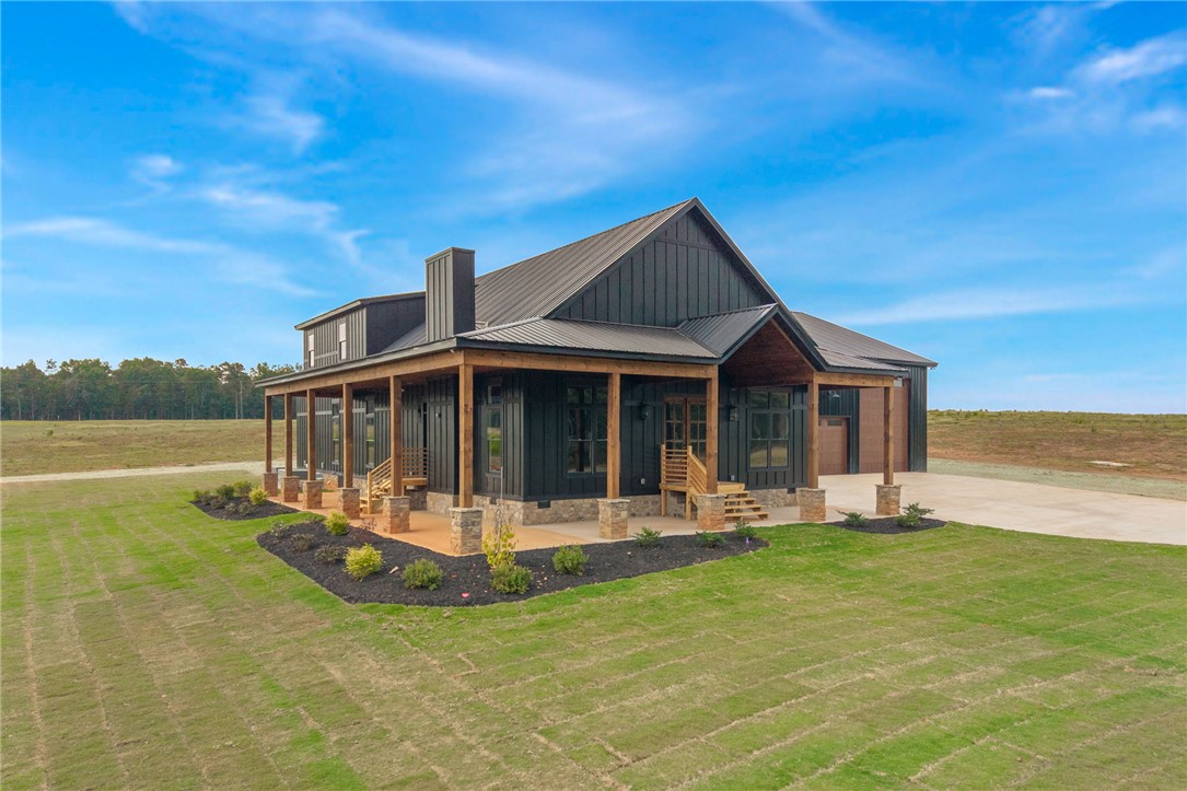 384 Jim Smith Road Pendleton, SC 29670 - Photo 3 of 48 Striking dark vertical siding paired with a wrap-around porch creates exceptional modern farmhouse curb appeal.