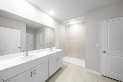 a bathroom with a double vanity sink and mirror with shower