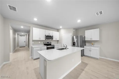 a kitchen with a sink a stove top oven a refrigerator and white cabinets
