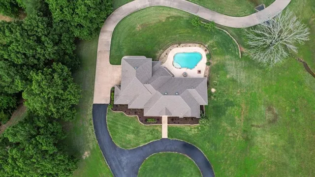 an aerial view of a house with outdoor space and trees all around