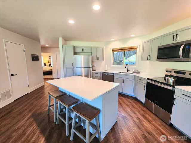 a kitchen with stainless steel appliances a dining table chairs microwave and sink