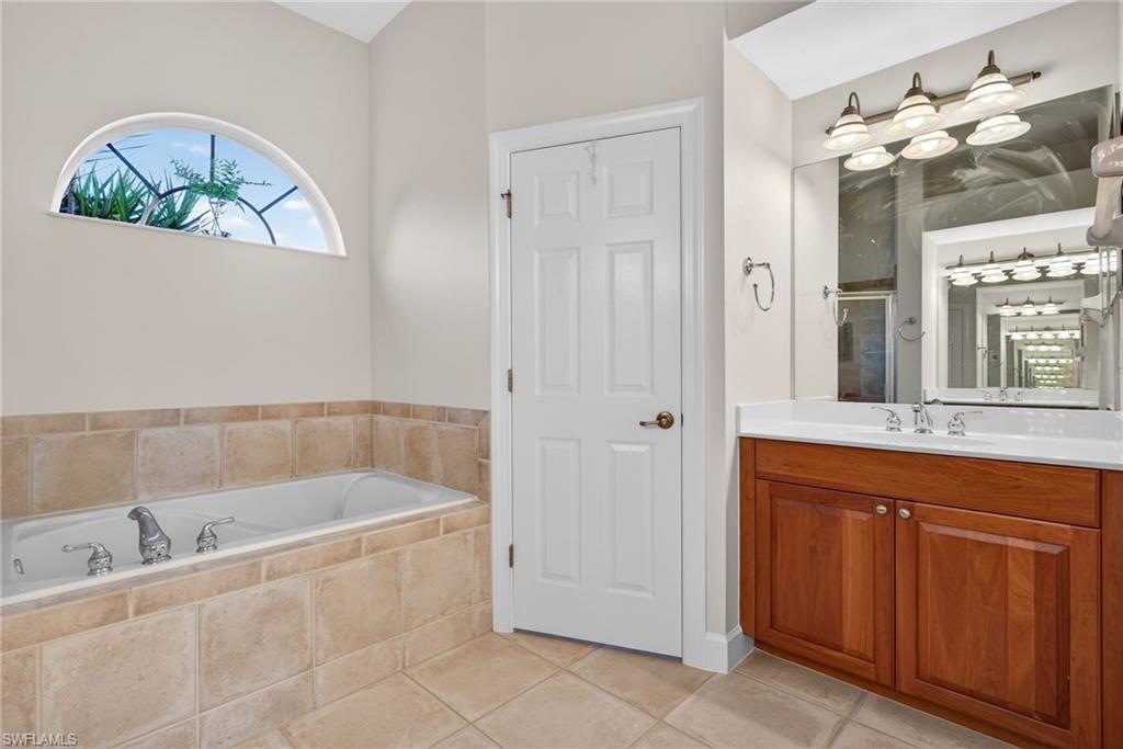 8968 Morgan Court Naples, FL 34113 - Photo 15 of 32 a bathroom with a tub sink and mirror