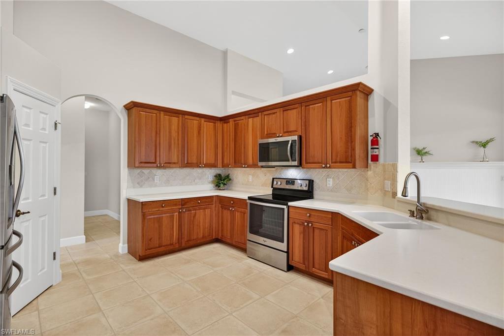 8968 Morgan Court Naples, FL 34113 - Photo 9 of 32 a kitchen with stainless steel appliances granite countertop a sink and dishwasher a stove top oven with wooden floor