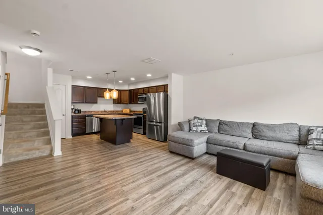 a living room with stainless steel appliances kitchen island granite countertop a couch and a view of living room