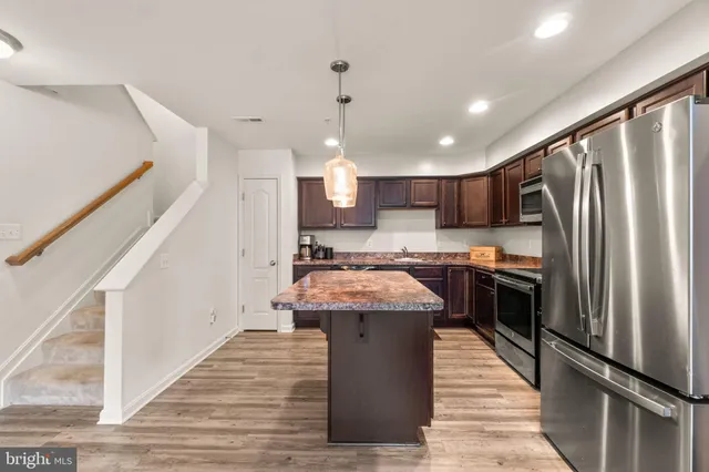 a kitchen with kitchen island a counter top space a sink stainless steel appliances and cabinets