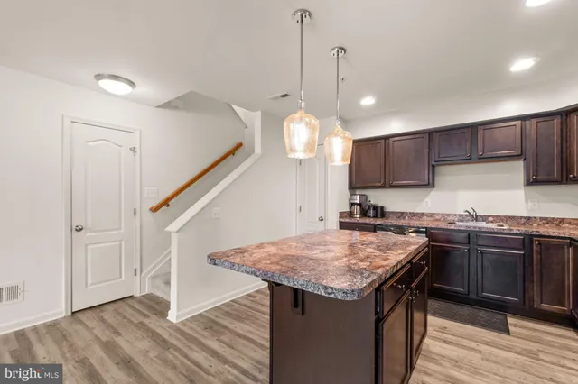 a kitchen with a center island wooden floor stainless steel appliances and cabinets