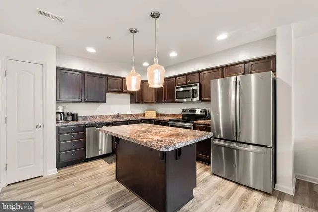 a kitchen with a refrigerator a sink and a stove top oven with wooden floor