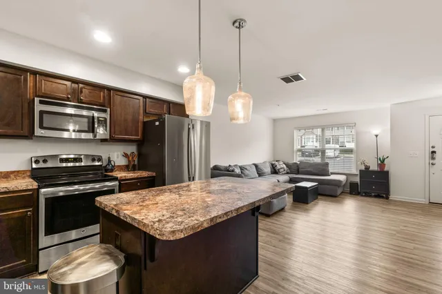 a kitchen with a stove a sink dishwasher a refrigerator and a dining table with wooden floor