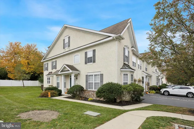 a view of a white house next to a yard with big trees