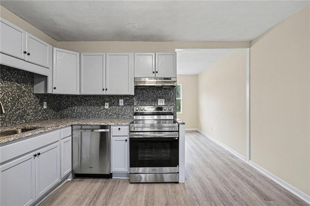 8355 Dunellen Lane Jonesboro, GA 30238 - Photo 16 of 27 a kitchen with cabinets wooden floor and stainless steel appliances
