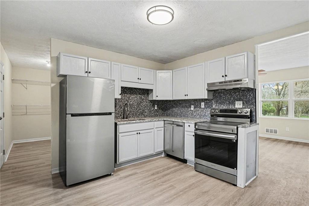 8355 Dunellen Lane Jonesboro, GA 30238 - Photo 2 of 27 a kitchen with cabinets stainless steel appliances and wooden floor