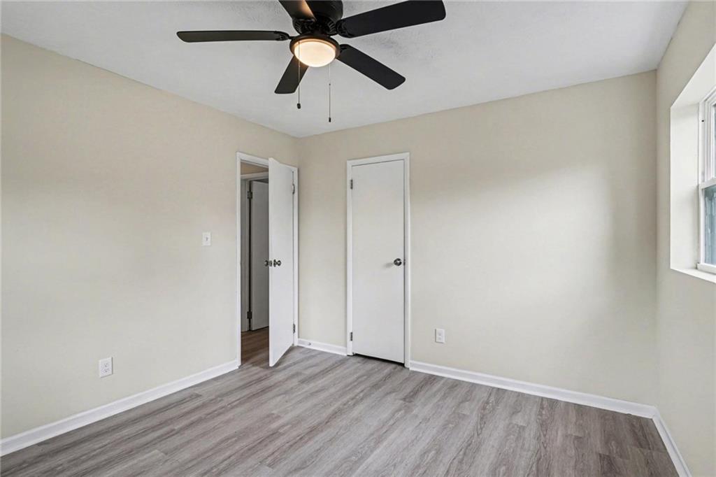 8355 Dunellen Lane Jonesboro, GA 30238 - Photo 23 of 27 an empty room with wooden floor ceiling fan and windows