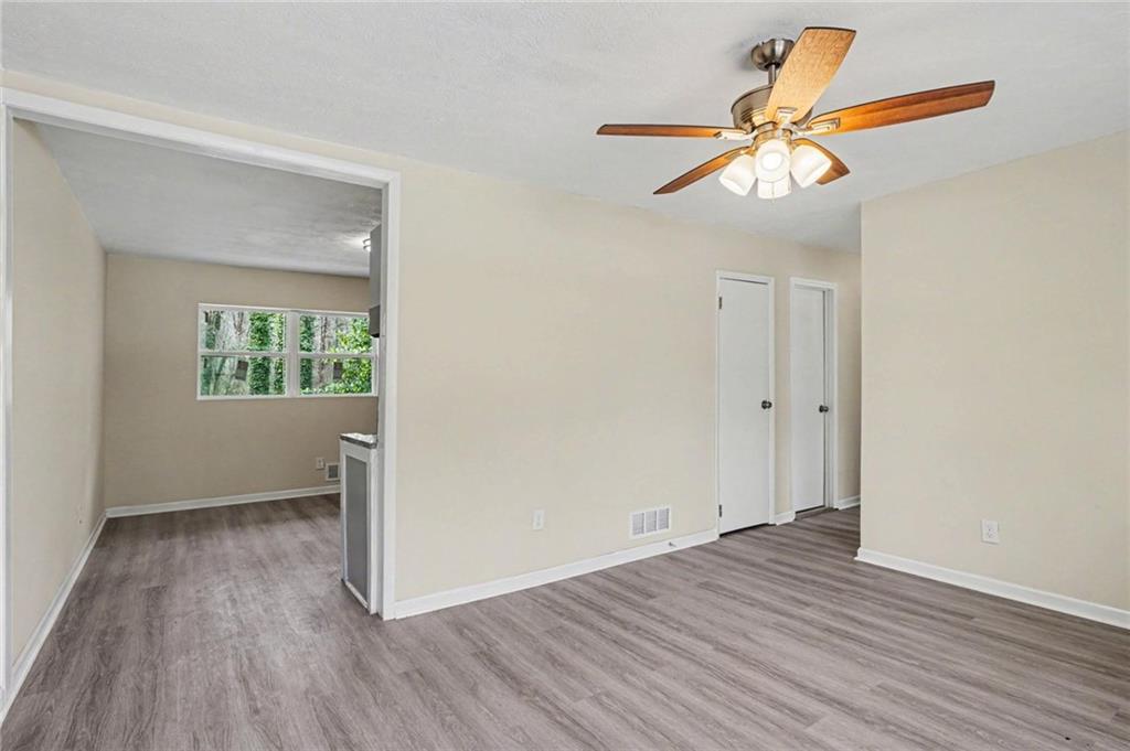 8355 Dunellen Lane Jonesboro, GA 30238 - Photo 5 of 27 an empty room with wooden floor chandelier fan and windows