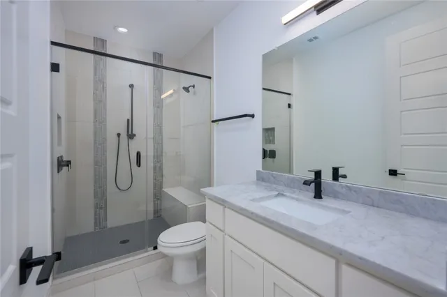 a bathroom with a granite countertop sink a toilet and shower