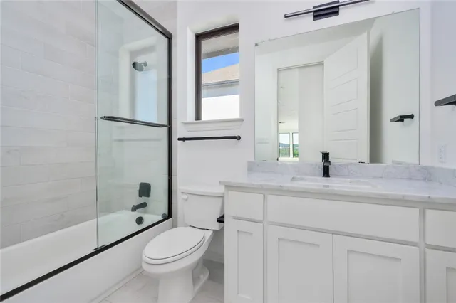 a bathroom with a granite countertop toilet a sink and a mirror
